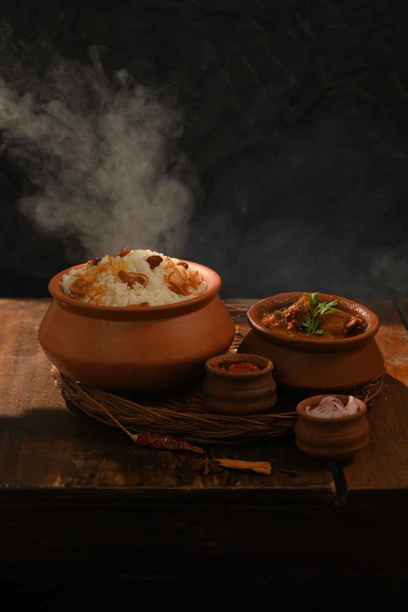 Steam rising from clay pots on a dark table.